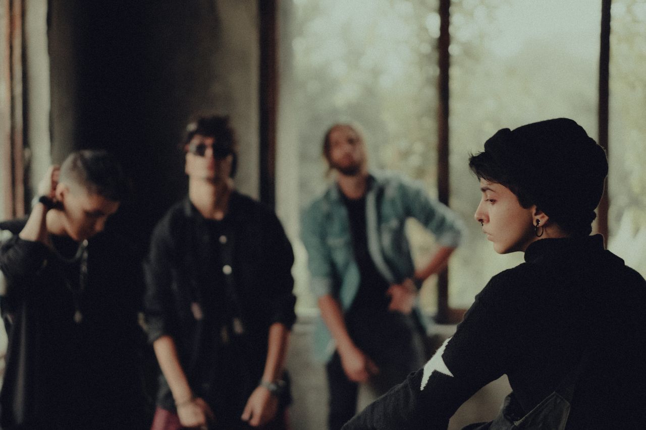 about-us-02 A fashionable group of young adults poses in a dimly lit room, evoking a sense of mystery.