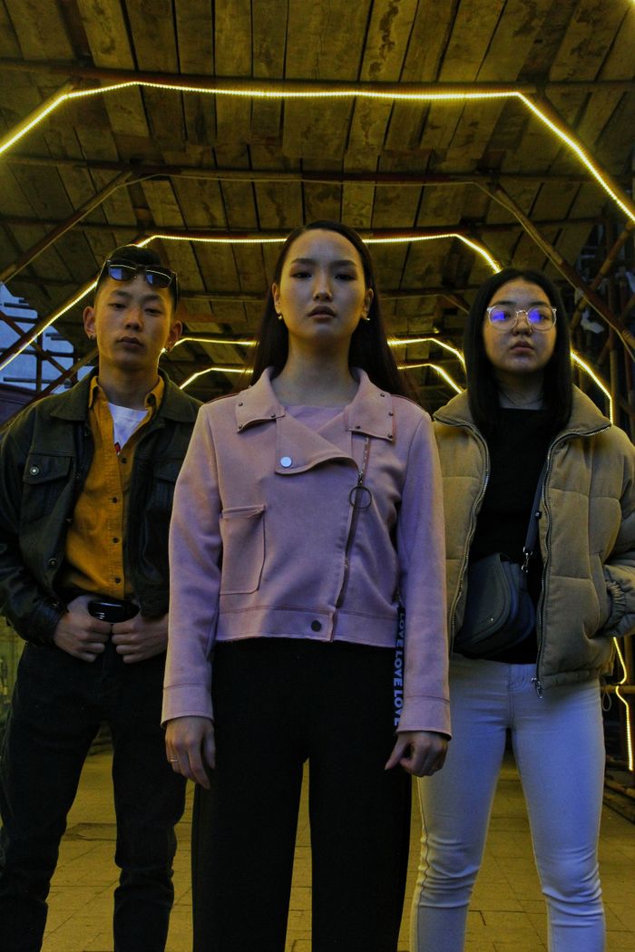 services-02 From below of young Asian friends in stylish clothes standing on street under roof with bright illumination