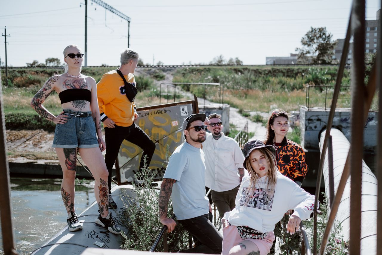 Fashionable group posing in streetwear by an industrial outdoor area.