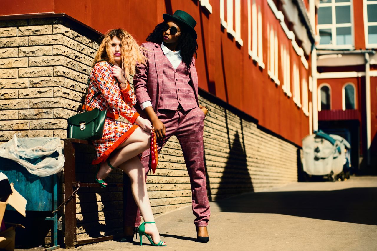 about-us-01 Fashionable duo posing outdoors in vibrant outfits, embracing urban style and confidence.